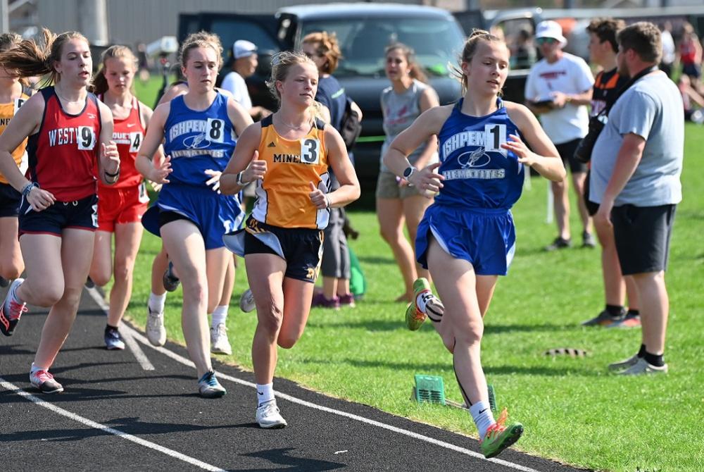 girls high school track athletes race to the finish line