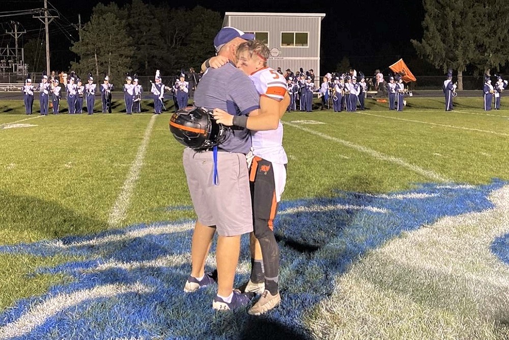North Branch coach Jeremy Ferman and Almont junior Bryce Ferman hug after last year’s matchup between their teams. 