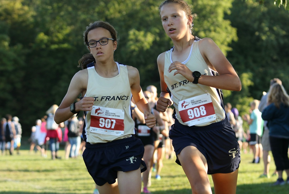 Grace Slocum (908) and Traverse City St. Francis teammate Grace Skendzel round a corner during a race this fall.