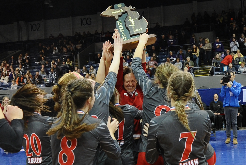 Players converge on Mount Pleasant Sacred Heart coach Krista Davis after she receives the Division 4 championship trophy Saturday. 