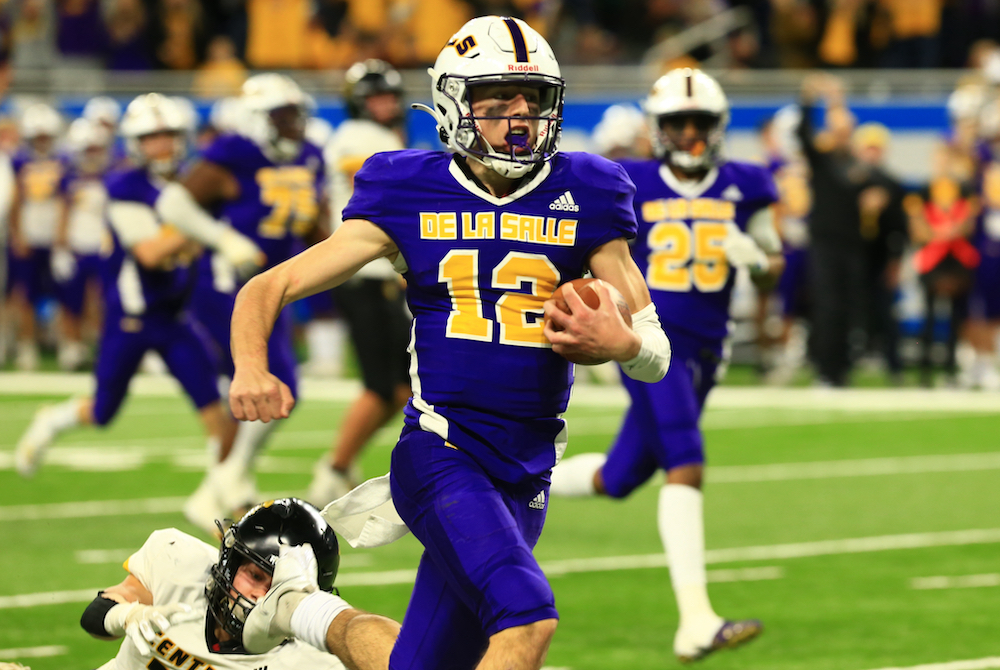 Warren De La Salle quarterback Brady Drogosh (12) pulls away from a Traverse City Central defender during last season’s Division 2 Final. 