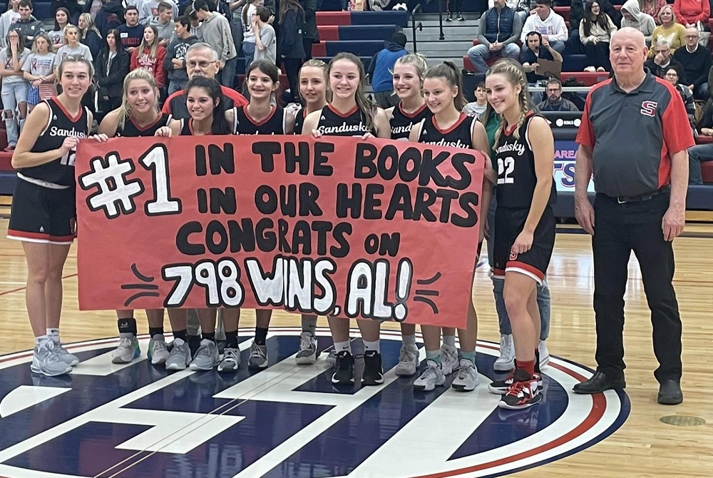 Sandusky girls basketball coach Al DeMott stands alongside his current team after they helped him break the MHSAA record for girls basketball victories Friday at Unionville-Sebewaing.