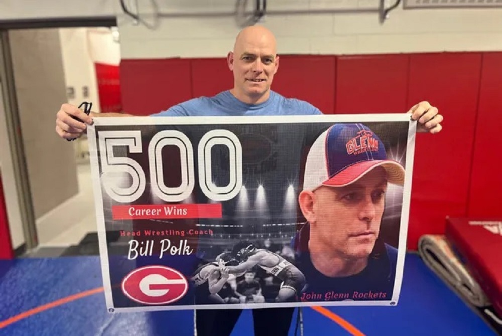 Westland John Glenn coach Bill Polk holds up a banner honoring his 500th victory. 