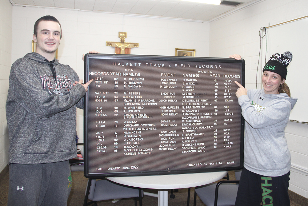 Hackett's Harrison Wheeler points to the pole vaulting record he hopes to break this season, while pole vaulting coach Shelly (Martin) Germinder points to the record she still holds at the school.