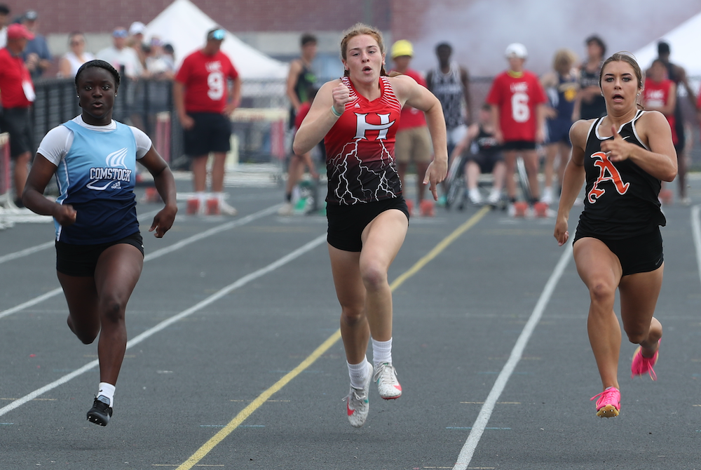 Hart’s Addi Hovey, center, sprints alongside Comstock’s Ti’Anna Murphy-Ryan, left, and Almont’s Devin Johnston.