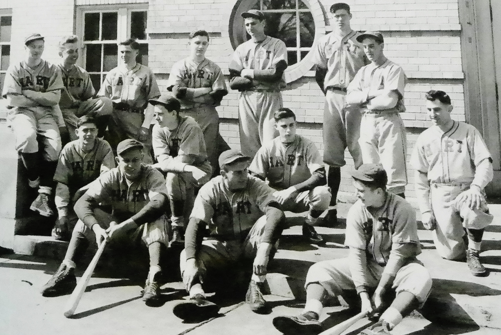 Members of the 1943 Hart High School varsity baseball team gather together, preparing for a team photo. Among those are Harold Gayle Tate (far left) and Walter "Stretch" Hansen, at 6-6 the tallest player in the back row. 