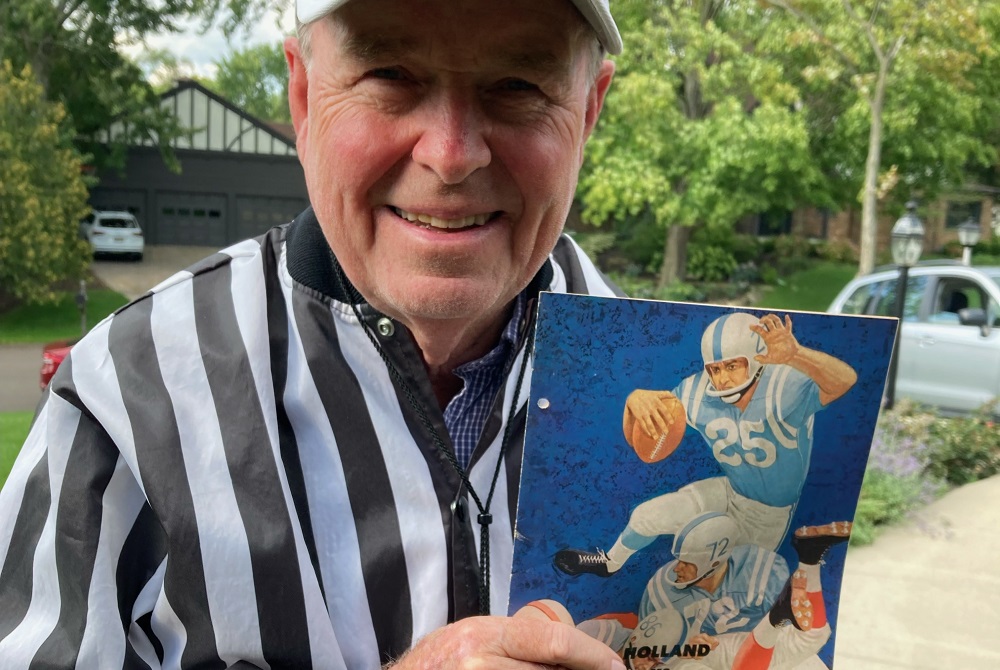 Tom Essenburg holds up a copy of the program from the 1962 game during which he intercepted a record five passes for Holland against Muskegon Heights. 