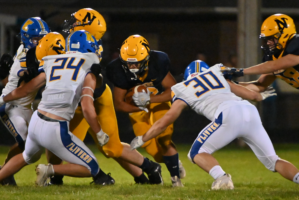 Negaunee's Kai Lacar gets a few yards before being tackled by Kingsford's Wyatt Scott (24) and Caleb Kleist (30).
