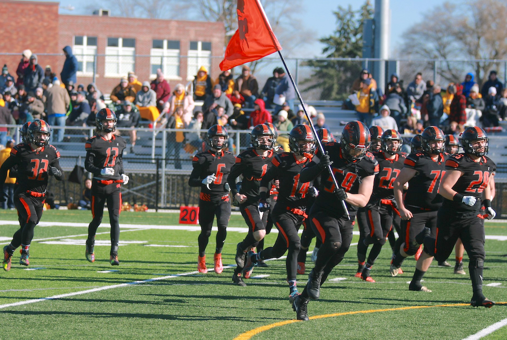 Senior Isaiah Bankston (59) leads Almont onto the field before last Saturday’s Semifinal win over Ovid-Elsie. 