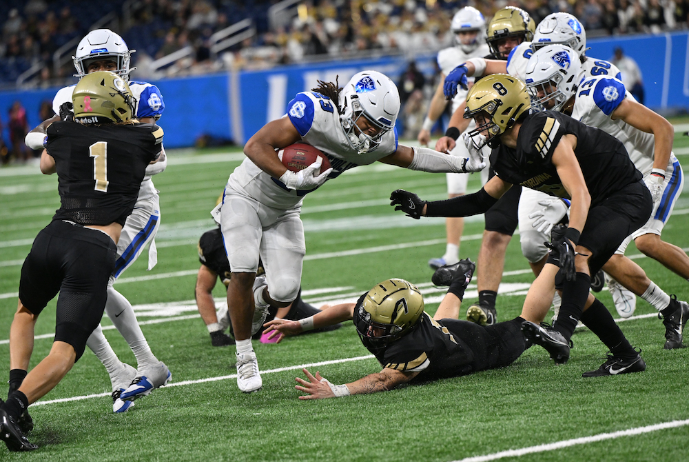 Grand Rapids Catholic Central’s Kellen Russell-Dixon (23) prepares for contact with Corunna’s Kaden Cowdrey (8) during Sunday’s Division 5 Final.