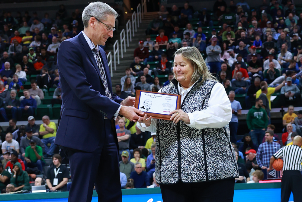 Frankfort’s Karen Leinaar accepts the 2023 Charles E. Forsythe Award from Grand Haven superintendent and MHSAA Representative Council president Scott Grimes during the Division 1 Boys Basketball Final in March.