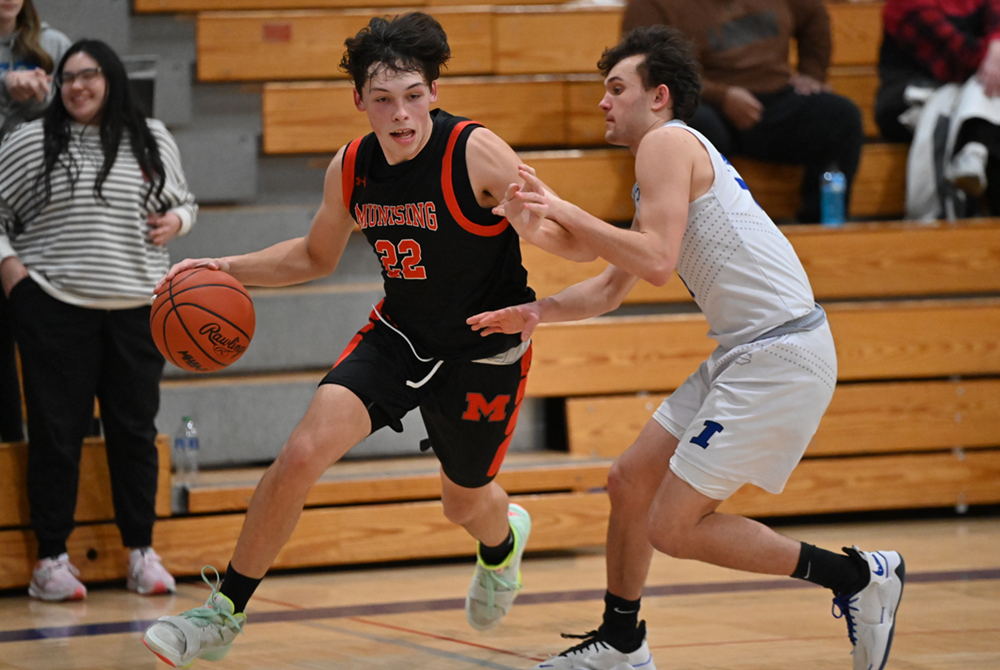 Munising's Jack Dusseault (22) drives toward the basket while being defended by Ishpeming's Ethan Corp during the Mustangs’ 54-48 win Dec. 28.