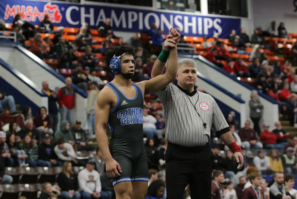 Darius Marines, left, has his hand raised in victory as he helps Detroit Catholic Central to a Division 1 Semifinal win Saturday at Wings Event Center.