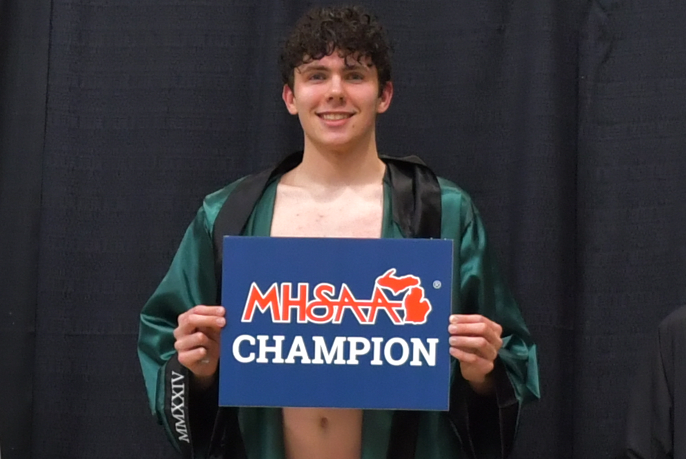 Birmingham Groves’ Angus MacDonald stands for a photo after receiving his medal for winning the 100 breaststroke Saturday at Eastern Michigan University.