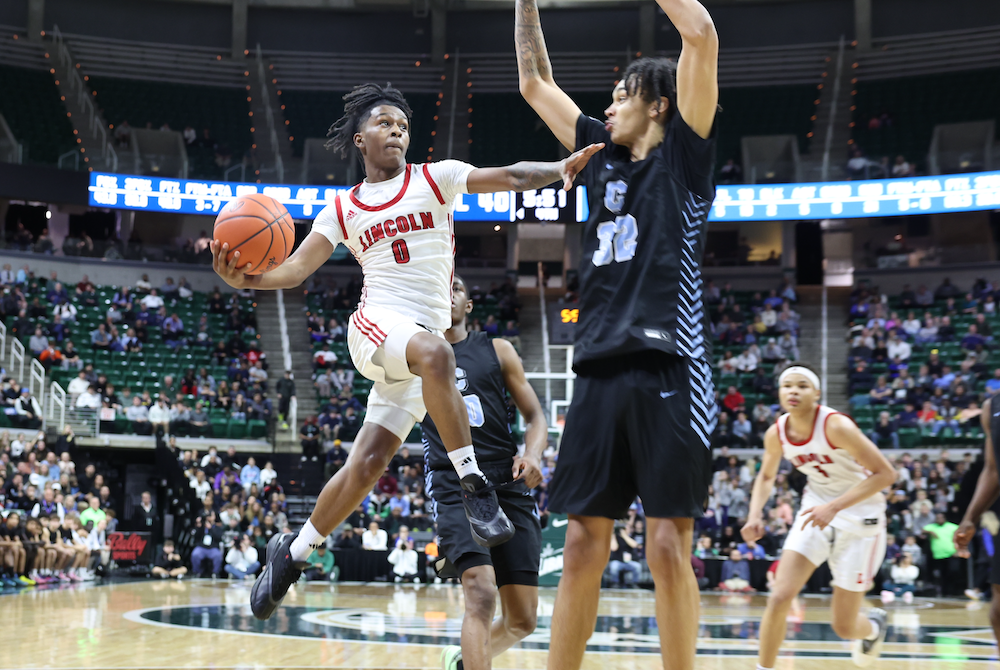 Warren Lincoln’s Moses Blackwell (0) soars into the lane as Grand Rapids Christian’s Jaylan Ouwinga (32) attempts to block his path Saturday night at Breslin Center.