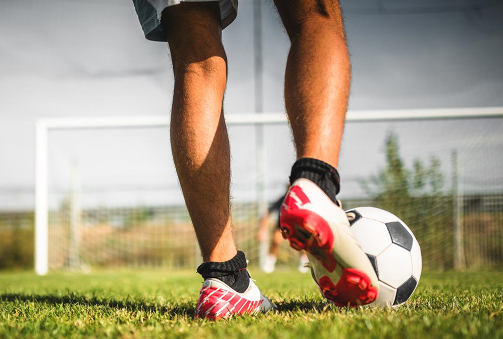 A person kicks a soccer ball toward a goal.