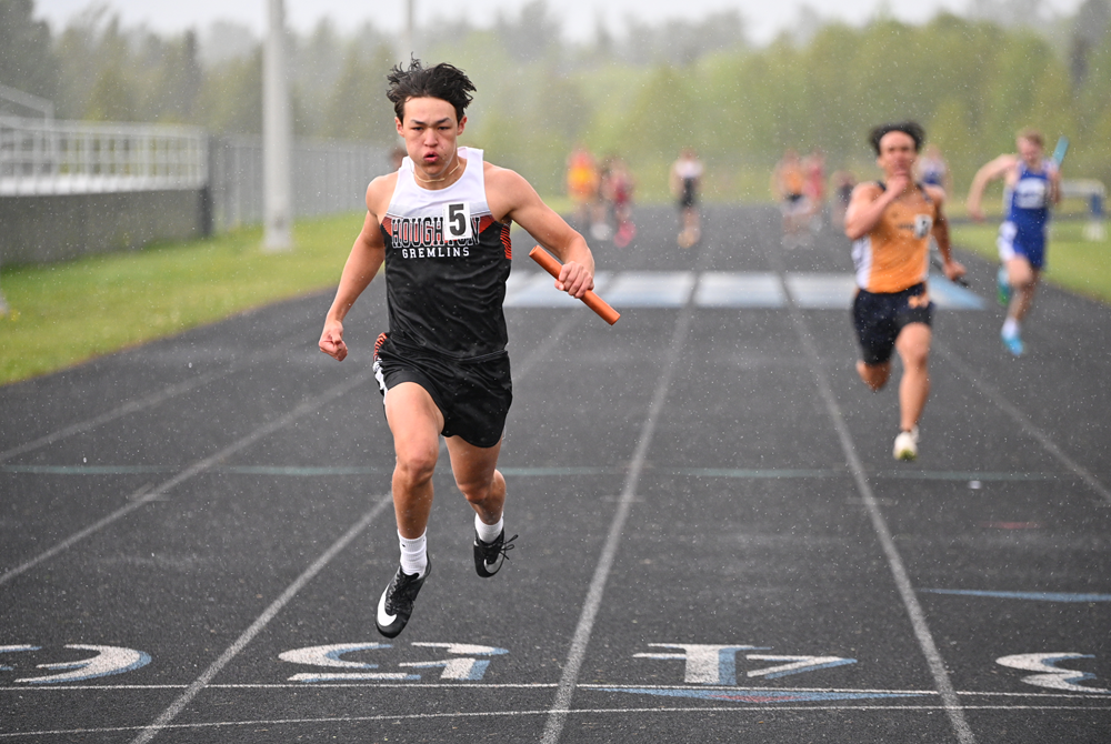 Houghton's Brody Mattila crosses the finish line during a downpour in the 400 relay at the Western Peninsula Athletic Conference championship meet May 22 in Ishpeming. 