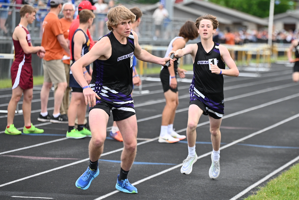 Pickford's Jacob Mitchell hands off the baton to Eli MacDonald for the last leg of the 3,200 relay Saturday at Kingsford. 