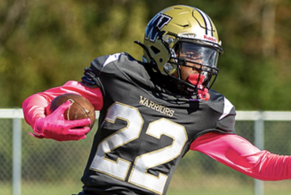 Flint Elite’s Phil Matthews carries the ball with a defender approaching.
