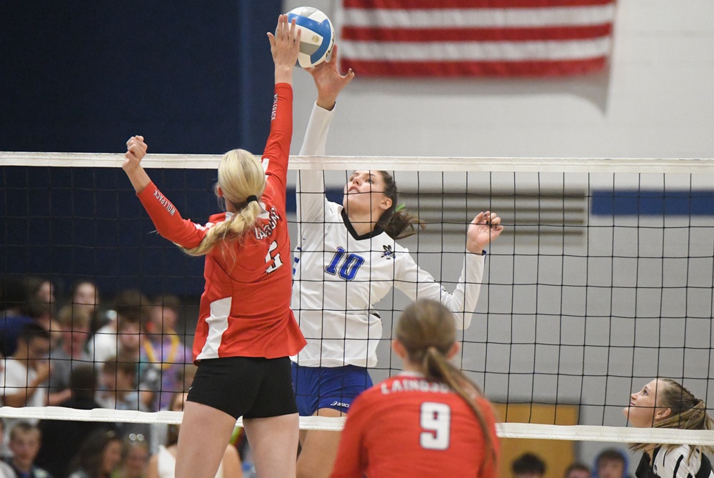 Laingsburg and Bath volleyball players meet over the net while connecting with the ball during a match Aug. 27.