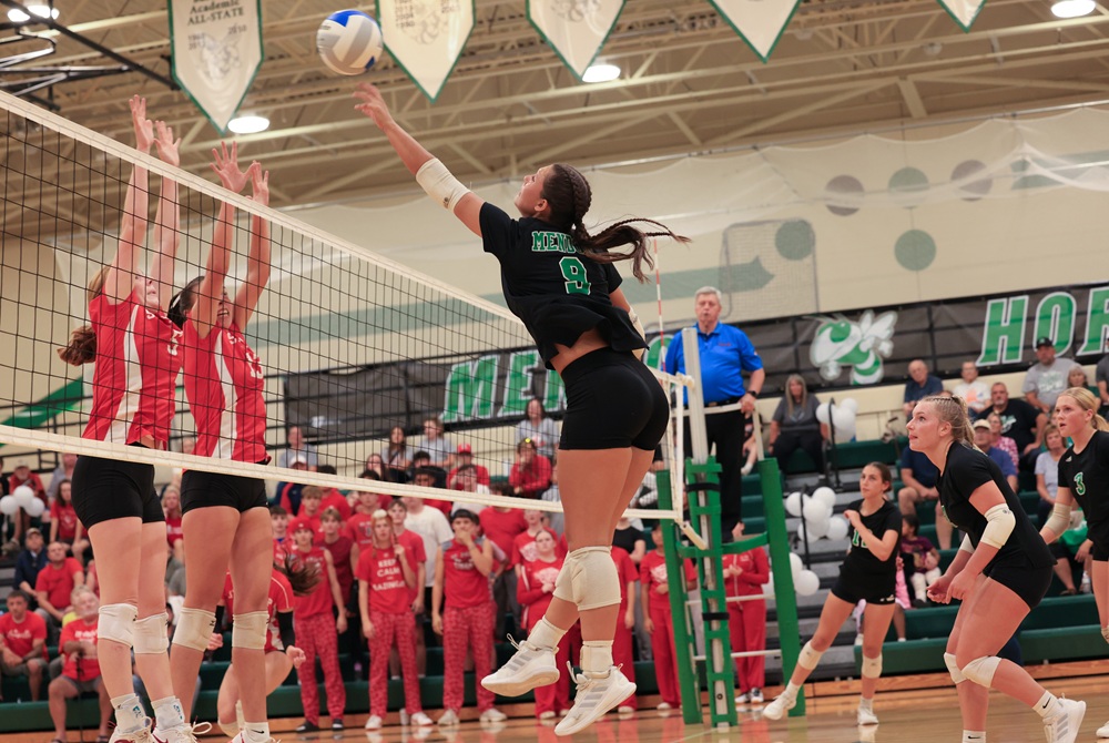Mendon senior right-side hitter Cienna Nightingale (9) attacks the net against a pair of Battle Creek St. Philip blockers last week.