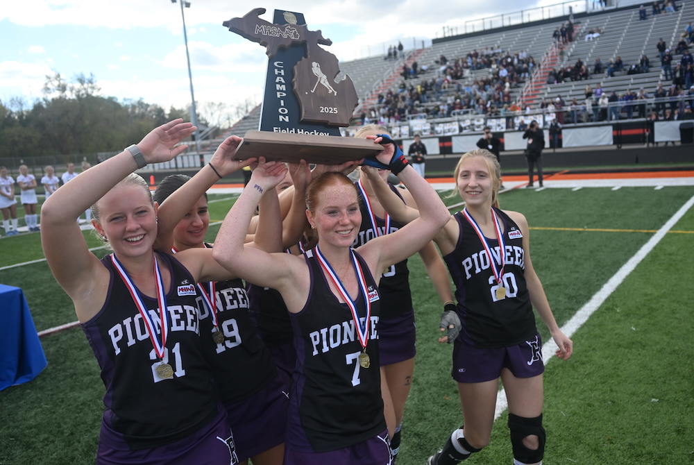 Ann Arbor Pioneer's Maggie Lamb (7) and her teammates raise their championship trophy Saturday after clinching the first MHSAA Finals title in the sport.