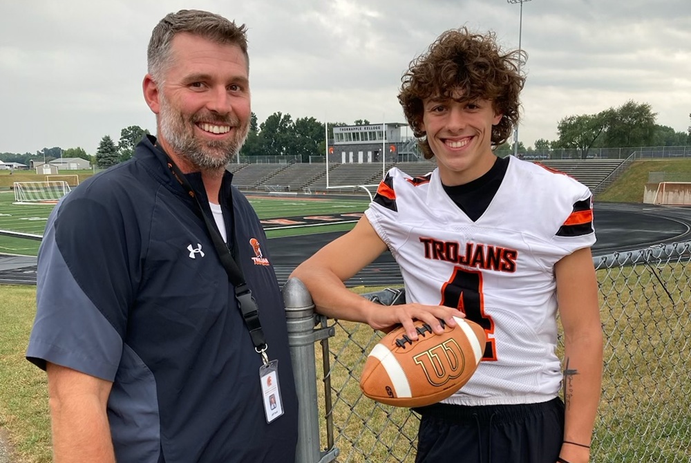 Jeff Dock, left, and son Micah – Middleville Thornapple Kellogg’s quarterback this season – stand for a photo at their home field.