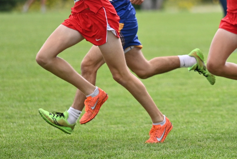 This photo is focused on two runners' legs and feet during a cross country race.