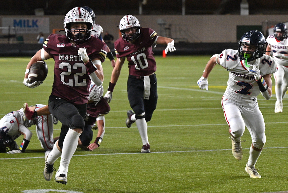 Martin’s Weson Elkins (22) charges down the sideline Saturday as Montabella’s Austin Jensen closes in during the Division 1 Final at Superior Dome.