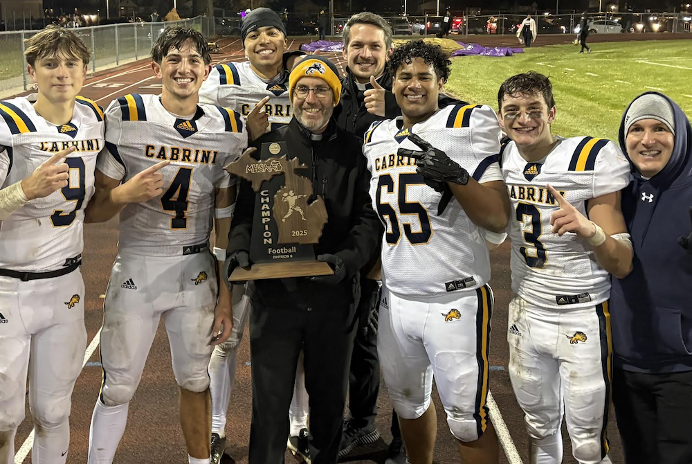 Allen Park Cabrini football players and coaches surround Fr. Tim Birney for a photo following a 34-32 win over Madison Heights Madison in their Division 8 Regional Final, which clinched the school's first Regional title. 