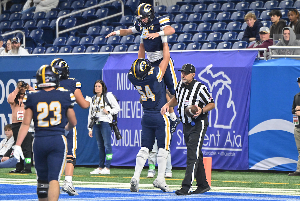 DeWitt’s Sam VanZee (54) hoists teammate Traverse Moore into the air in the end zone Sunday. 