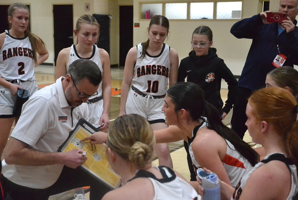 Manton’s Aubrey Hiller points something out on her coach’s clipboard during a break against LeRoy Pine River.