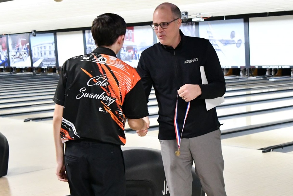 MHSAA senior assistant director Andy Frushour, right, passes out a medal during Bowling Finals. 