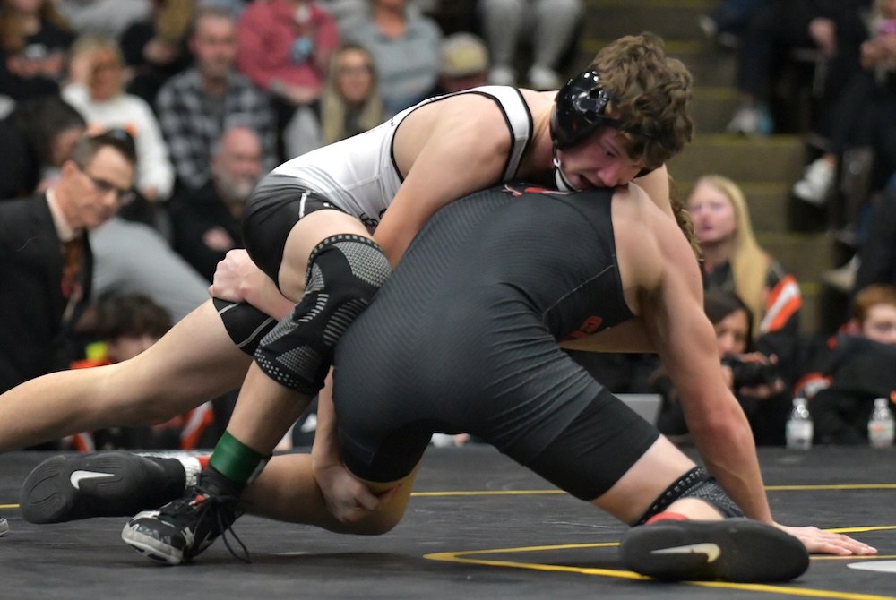 Hudson’s Colt Perry works toward a decision at 150 pounds under the watchful eye of coach Scott Marry, far left. 