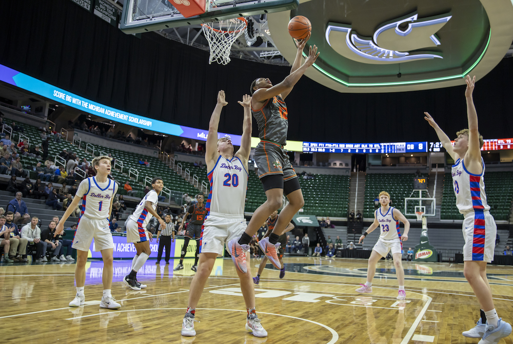 Detroit Douglass’ Kamari Howard (12) gets a shot up over Dollar Bay’s Liam Tourtillott (20) during Thursday’s first Division 4 Semifinal at Breslin Center.
