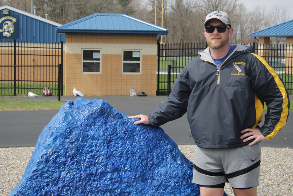 Adrian Madison track & field assistant coach Trevor Van Valkenburg stands at the entrance to the school’s track this spring. 
