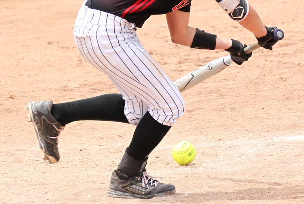 A bunted softball lands in fair territory just beyond the batter's box.