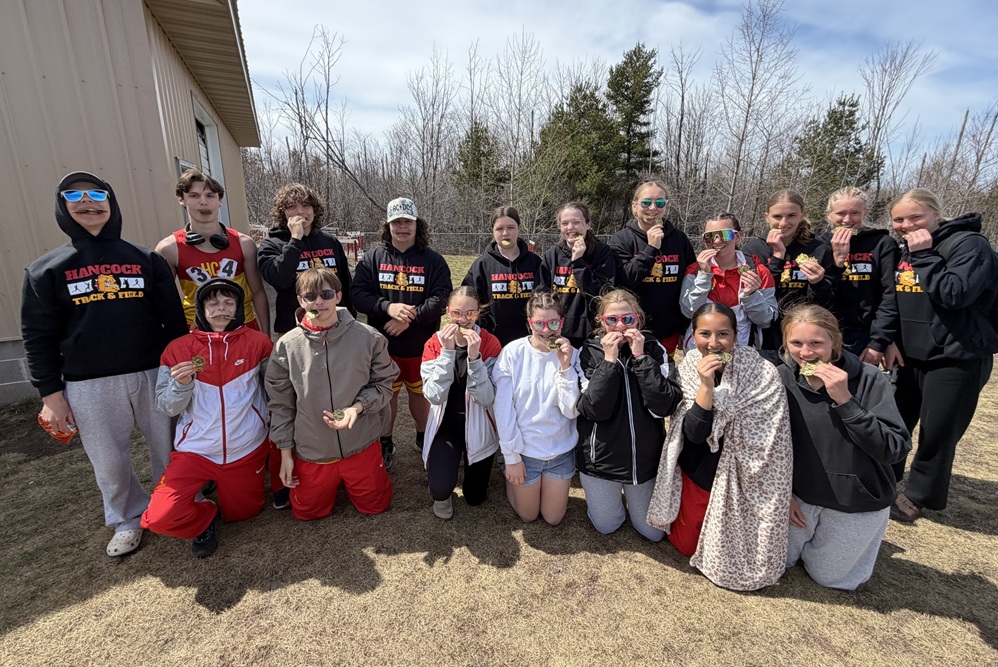Hancock athletes bite down on their medals won at their home invitational.