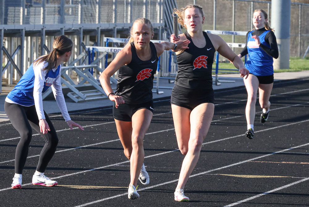 Sydney Bir, right, hands off the baton in the 800-meter relay to senior teammate Kinder Smith during a meet.