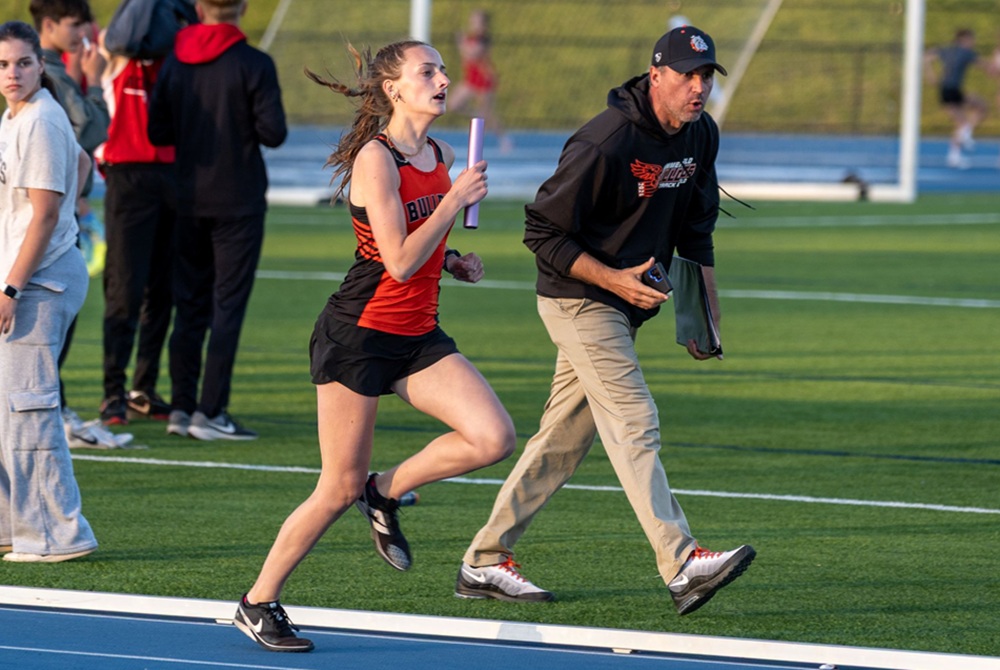 Petersburg Summerfield coach David Raymond encourages Allison Ost during a relay race this season.
