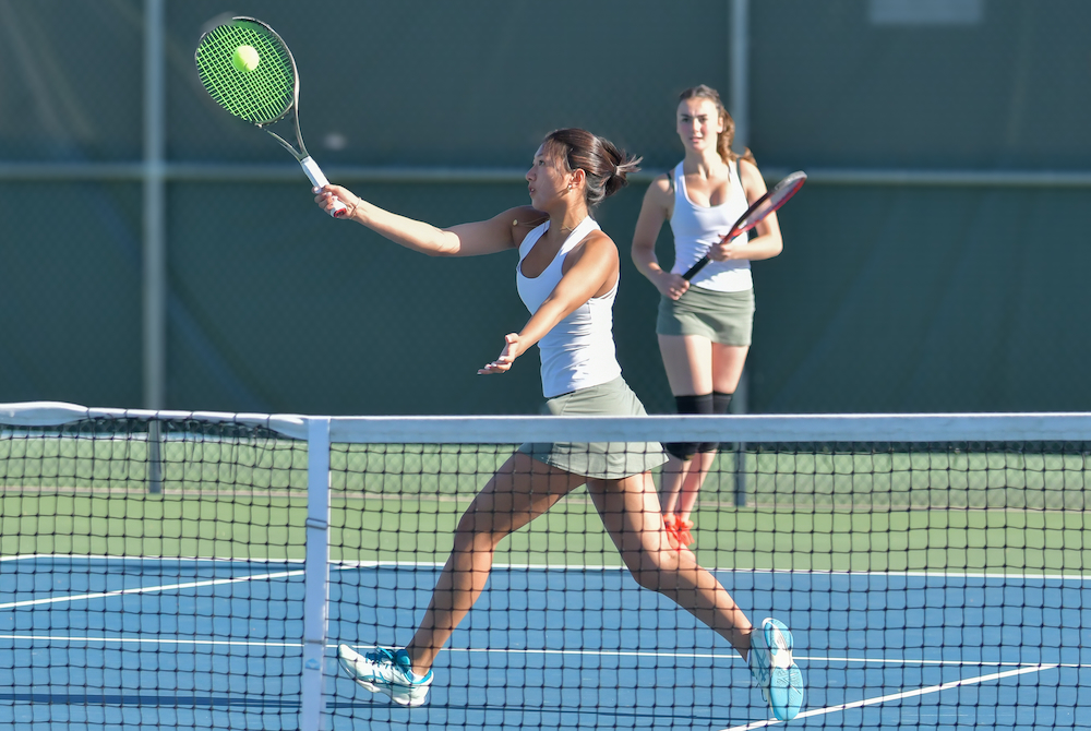 A Greenhills doubles player connects with a volley at the net. 