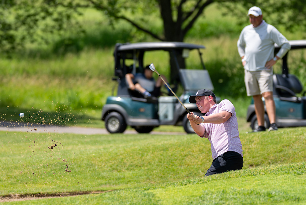 Charlevoix’s Bryce Boss punches out of a sand trap during his second round Saturday at Forest Akers West.