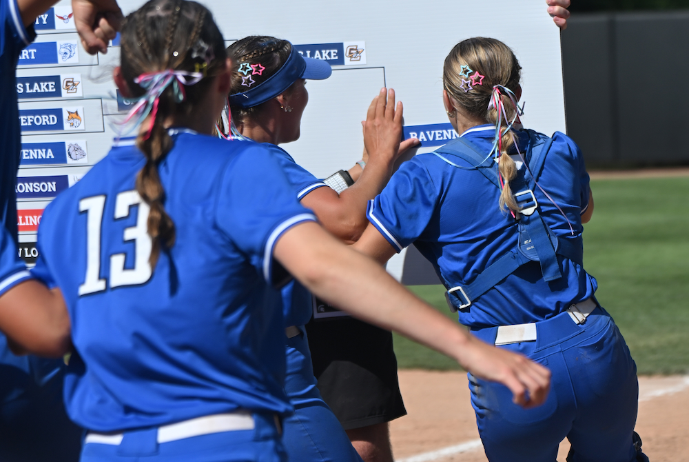 Ravenna catcher Emily Postema and her teammates plant their school down on the bracket after clinching the Division 3 title Saturday at Secchia Stadium.