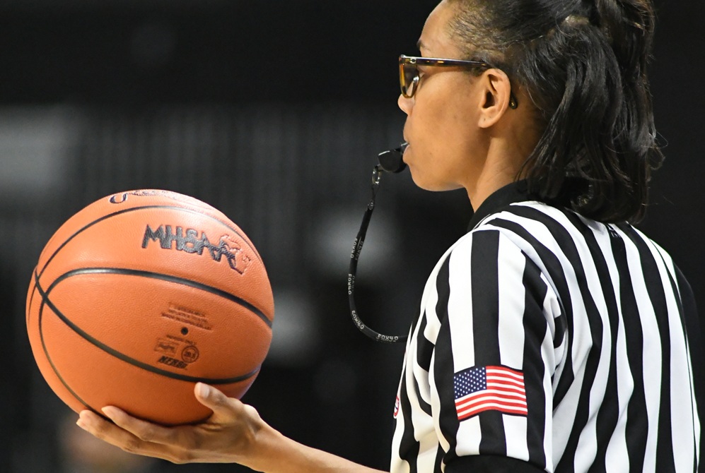 A basketball official holds a basketball during a break in a game. 
