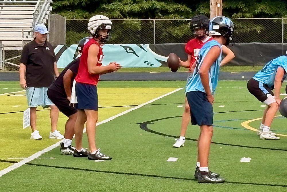 Forest Hills Northern coach Eddie Ostipow, far left, watches his senior son run the offense during Monday’s first practice of the season. 