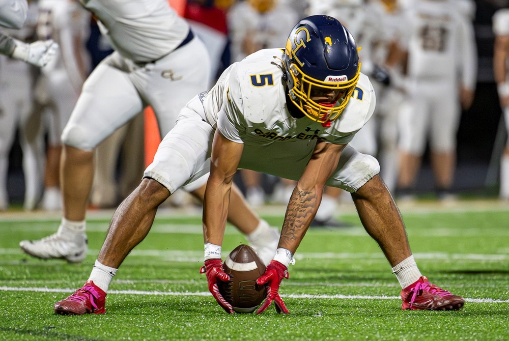 A Grand Ledge football players picks a ball up from the ground during a 2025 game.