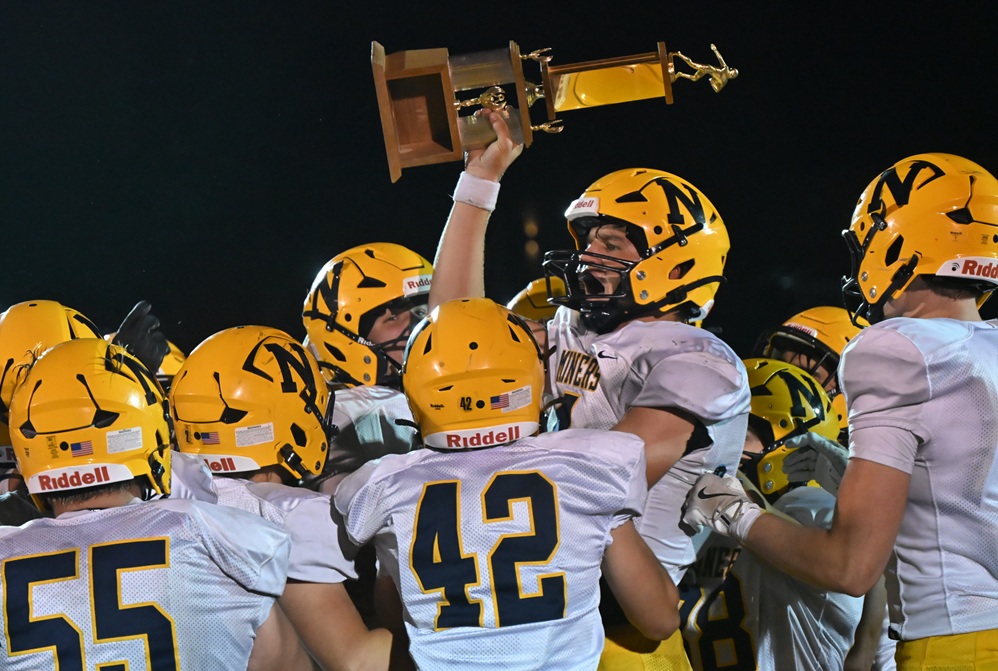 Negaunee's Kyle Waterman hoists the Jubilee trophy over his head after his team defeated Marquette.