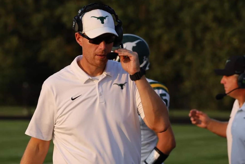 Sand Creek assistant football coach Sid Disbrow mans the headset while on the sideline during a game.