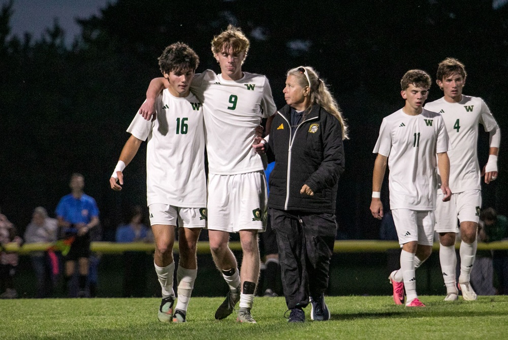 Traverse City Central trainer Amy Ream escorts an injured Traverse City West player off the field during Thursday’s game.