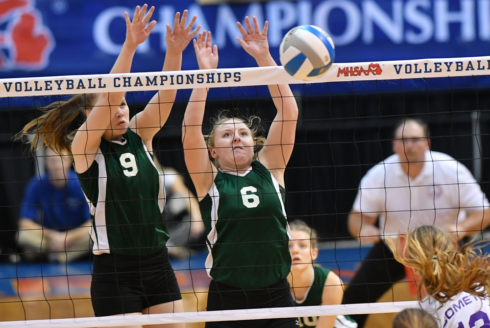 Two Carney-Nadeau volleyball players block a kill attempt by Leland during the 2018 MHSAA Semifinals.